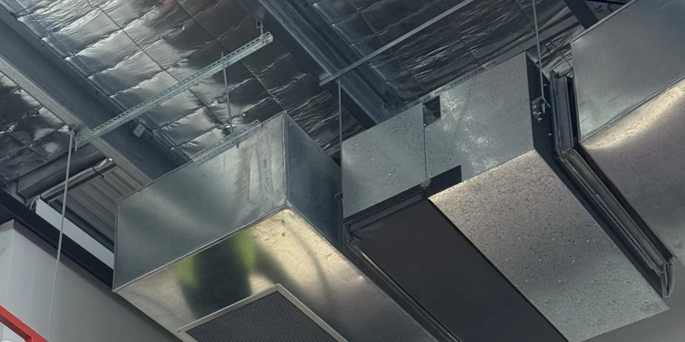 Ductwork and air vent grilles in the gym roof space during the clean