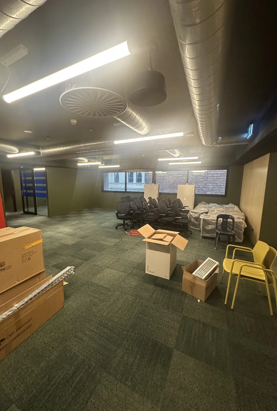 An open-plan office floor before the clean, with boxed furniture and packaging left after the building work