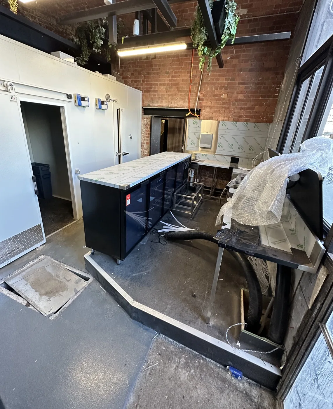 The bar servery before the clean, with plastic wrap, loose hoses and construction debris across the floor