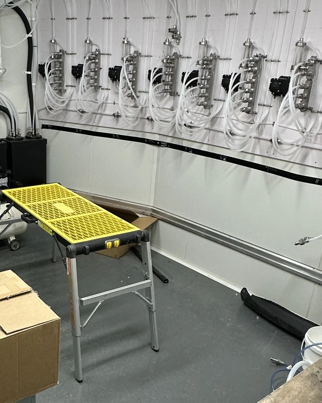 The keg cool room before the clean, with a folding work platform, a cardboard box and a loose hose left on the floor from the build
