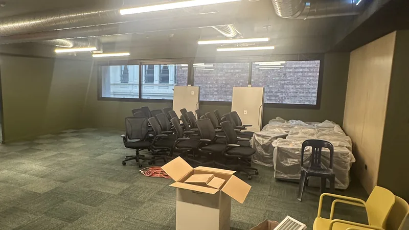 An open-plan office floor with boxed furniture and packaging left after building work