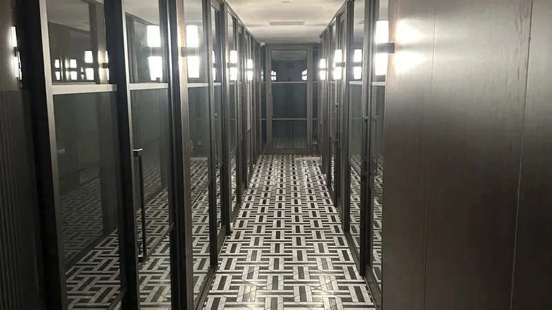 A glass-partitioned office corridor with a patterned tile floor