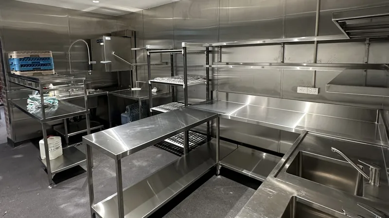 Stainless steel prep benches, shelving and sinks in an empty commercial kitchen