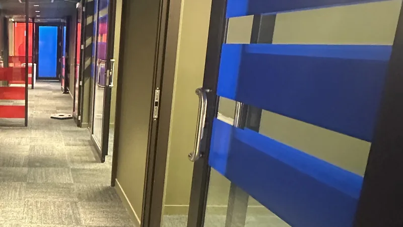 A building corridor with carpet and glass doors banded in blue