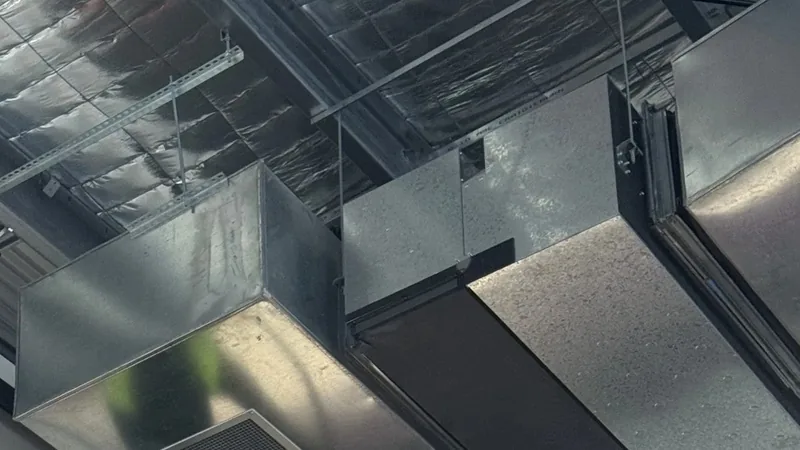 Ductwork and air vent grilles mounted high above a Melbourne gym floor