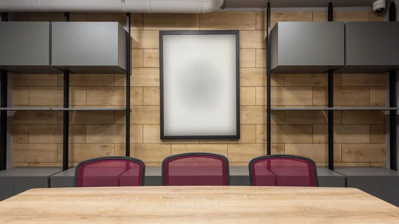 A meeting room with a timber table, red mesh chairs and overhead cabinets