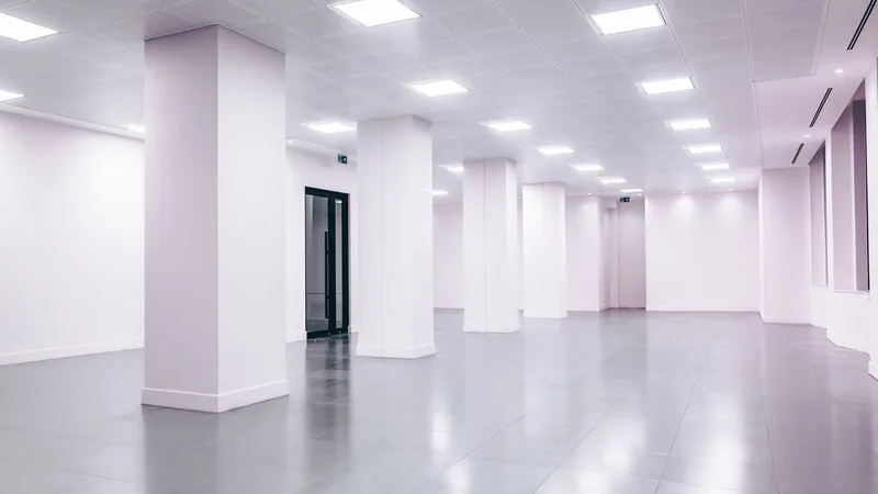 An empty white office floor with square columns and recessed ceiling lights