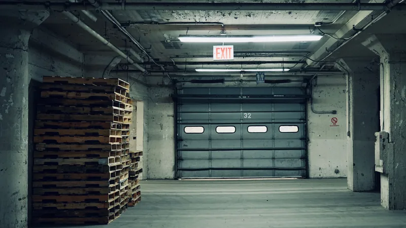 An empty warehouse with stacked timber pallets and a closed roller door