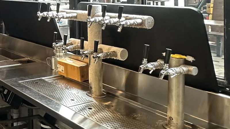 A stainless steel bar bench, drip trays and beer taps in a newly built Melbourne bar after a builders clean